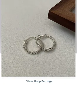 Detailed close-up of S925 sterling silver hoop earrings with irregular hammered texture