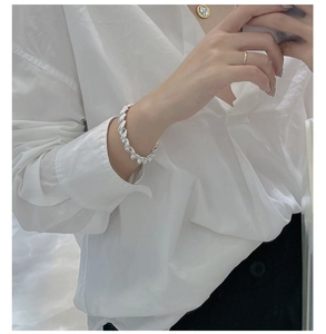 Détail d'un bracelet corde en argent S925 porté avec un collier médaille dorée