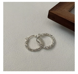 Macro shot of S925 sterling silver hoop earrings with a pleated textured finish