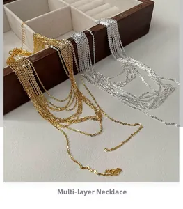 Detailed close-up of minimalist layered gold and silver chains on a jewelry box