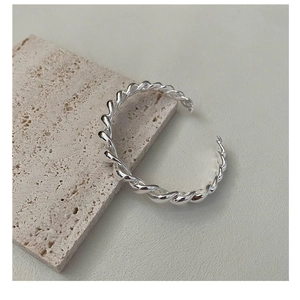 Vue macro d'un bracelet torsadé en argent sur un support en pierre texturée