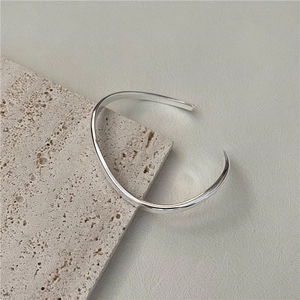Minimalist S925 sterling silver open bangle with polished wavy curves on stone background