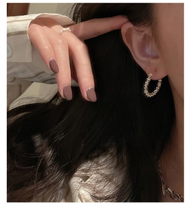 Detail of silver textured hoop earring with a beaded stack design on a female model