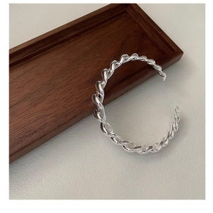 Gros plan détaillé du bracelet jonc torsadé en argent S925 sur un support en bois