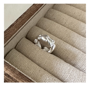 Detail of S925 sterling silver heart-shaped chain ring on beige linen jewelry box tray