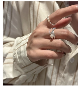 Macro detail of elegant stacked S925 silver pearl ring and fluid metal chain ring