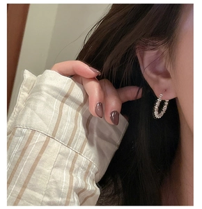 Detailed view of silver hoop earrings with bead texture on a model in a warm setting