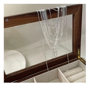 Detail of layered S925 sterling silver tassel necklace draped over a vintage wooden jewelry box