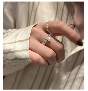 Detail of vintage S925 silver rings with pearls worn on hand against a shirt background