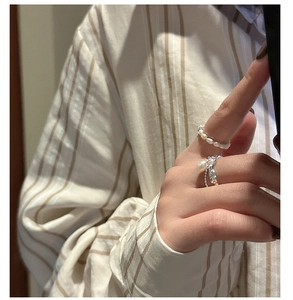 Detail of stacked S925 silver rings with irregular texture and elegant white pearls