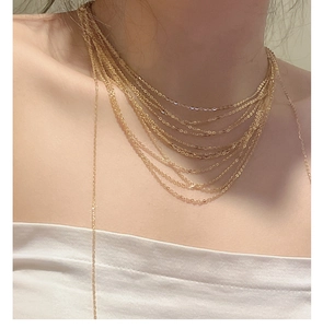 Detail shot of a golden multi-layered fine chain necklace on a model's neck