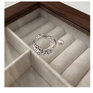 Macro shot of silver irregular lava texture ring with pearl in a beige velvet jewelry box