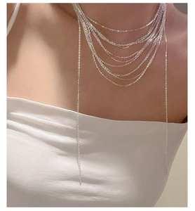 Detail of layered S925 sterling silver tassel necklace on female model neck