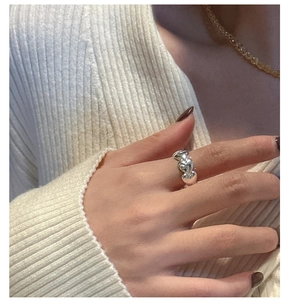 Detail of S925 sterling silver heart-shaped band ring worn on finger with a cozy background