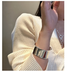 Primer plano de brazalete de plata pulida de banda ancha en modelo con punto fino