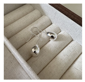 Macro shot of polished S925 sterling silver teardrop earrings on linen jewelry box