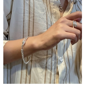 Detail of S925 sterling silver abacus bead bracelet and cross ring on a hand