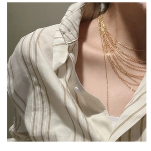 Detail of layered gold tassels necklace showing multiple strands on a model neck