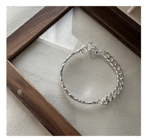 Detail of silver S925 bracelet with twisted texture and chunky Cuban link chain combo