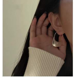 Detail showing the curved S925 sterling silver plate earring worn by a model
