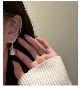 Close-up of elegant S925 sterling silver waterdrop earrings worn on ear with mirror finish