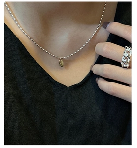Détail macro du collier en argent S925 avec pendentif LOVE et bague chaîne épaisse
