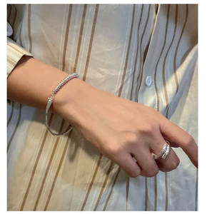 Close-up of S925 sterling silver bead bracelet and layered ring set on a model