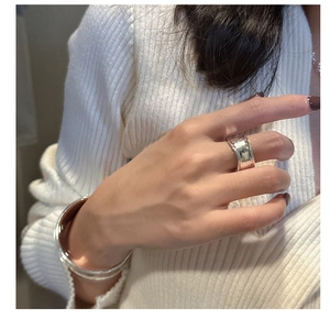 Anillo ancho y brazalete de plata de ley S925 pulida en la mano de la modelo