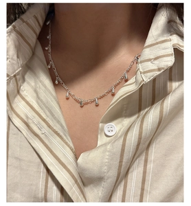 Close-up of S925 sterling silver drop tassel necklace on model wearing beige striped shirt