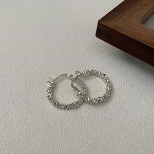 Elegant S925 sterling silver hoop earrings with irregular hammered texture on white surface