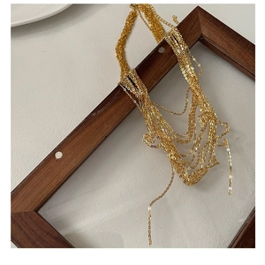 Detail of layered gold fine chain necklace draped over a vintage wooden frame display