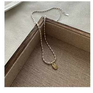 Détail du collier à billes en argent S925 avec pendentif doré gravé LOVE sur lin rustique