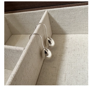 Detail of S925 sterling silver teardrop earrings on a beige linen jewelry display