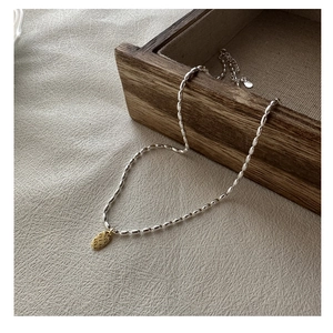 Détail macro du collier en perles d'argent S925 avec pendentif doré gravé LOVE