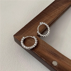 Elegant S925 sterling silver beaded hoop earrings displayed on a dark wood and white background