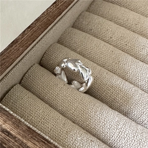 Polished S925 sterling silver ring with hollow heart patterns on a linen display