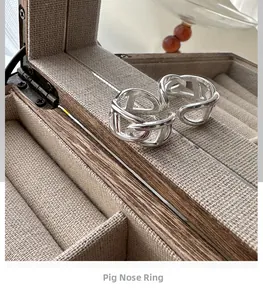 Detail of adjustable S925 sterling silver pig nose rings on a soft fabric jewelry box