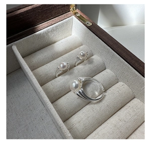 Close-up of three S925 sterling silver pearl rings with textured bands in a wooden jewelry box