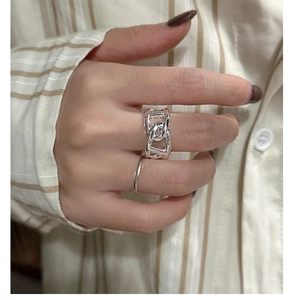 Close-up of S925 silver pig nose chain rings worn on a hand over a striped shirt