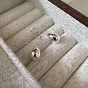 Polished S925 sterling silver teardrop earrings on beige fabric jewelry box tray