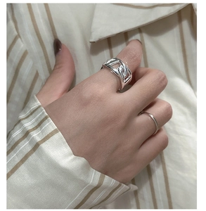 Macro detail of silver S925 interlocking chain ring worn on finger with layered styling
