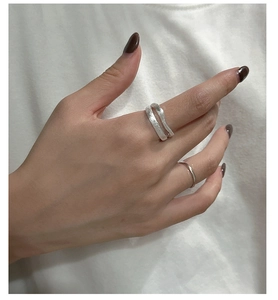 Macro view of layered wavy silver ring with brushed texture on female finger