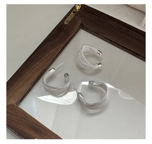 Macro detail of silver S925 multi-strand woven hoop earrings and ear cuff in jewelry box