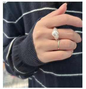 Detail of stacked S925 silver rings with large white pearl on model's finger