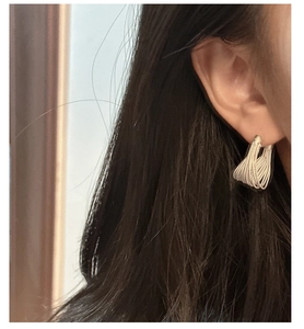 Detailed close-up of multi-layer silver twisted wire hoop earring worn by a model