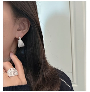 Detail of silver S925 multi-strand layered earrings and ring worn by a model