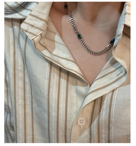 Close-up of S925 silver necklace with rectangular green zircons on a model's neck