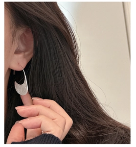 Detailed view of brushed S925 silver crescent earrings worn by a model