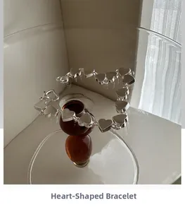 Detailed view of silver heart-shaped bracelet draped over a glass container