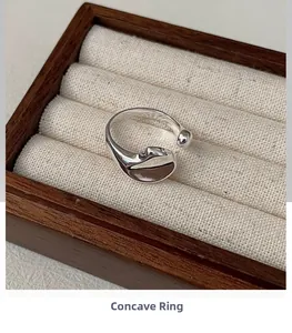 Macro shot of polished S925 sterling silver concave ring on a beige wooden jewelry box